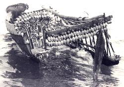 [front view of Trobriand canoe showing double string of large cowry shells strung between the canoe and the outrigger: 14k]